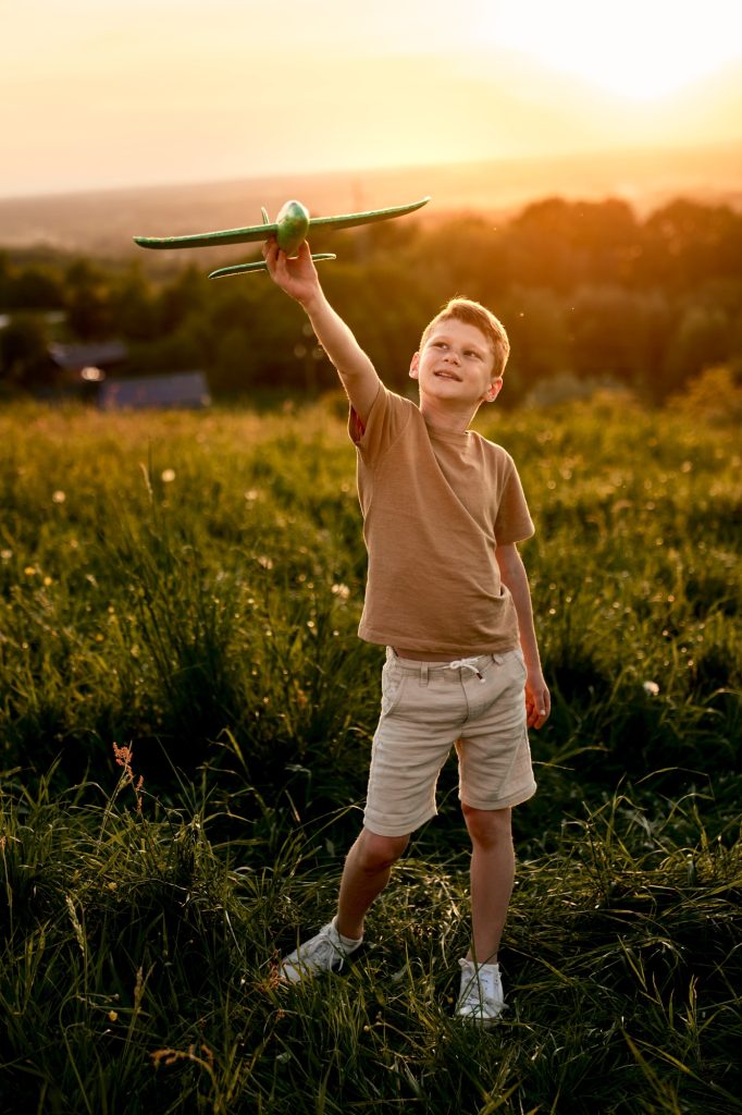 Little boy holding toy airplane on the meadow